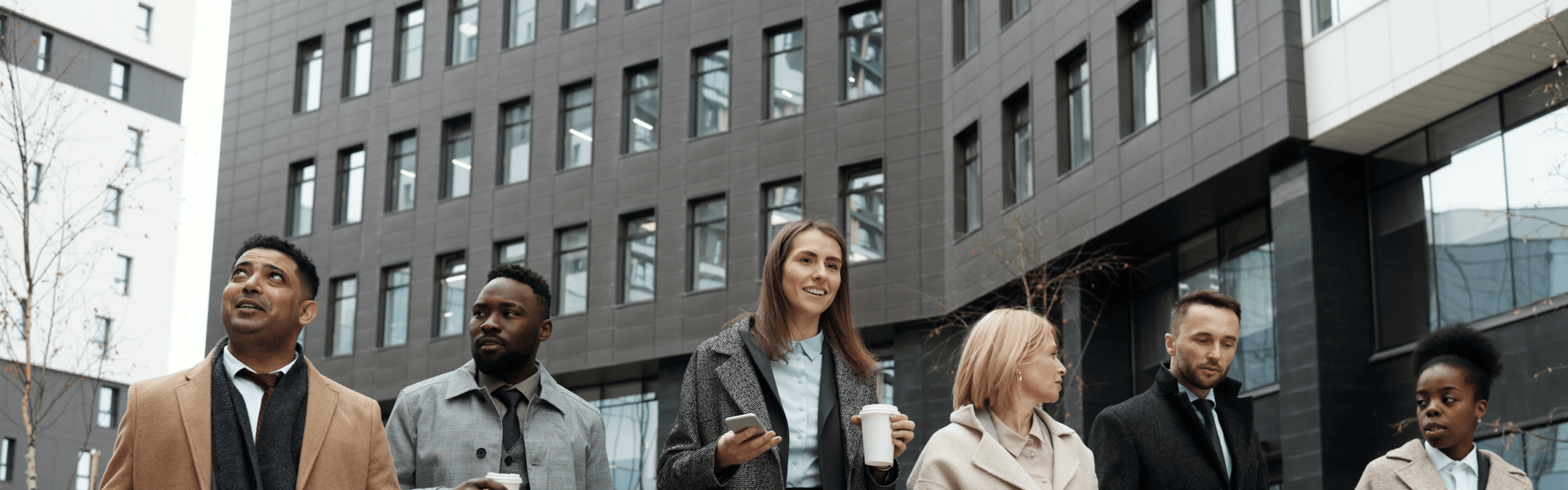 A group of six professionals walking through a business district with skyscrapers
